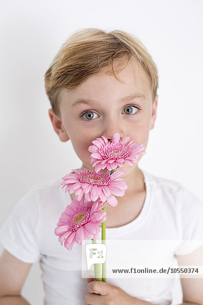 Young boy posing for a picture in a photographers studio  holding a bunch of flowers.