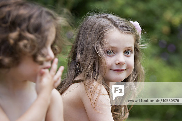 Zwei lächelnde junge Mädchen bei einer Gartenparty.