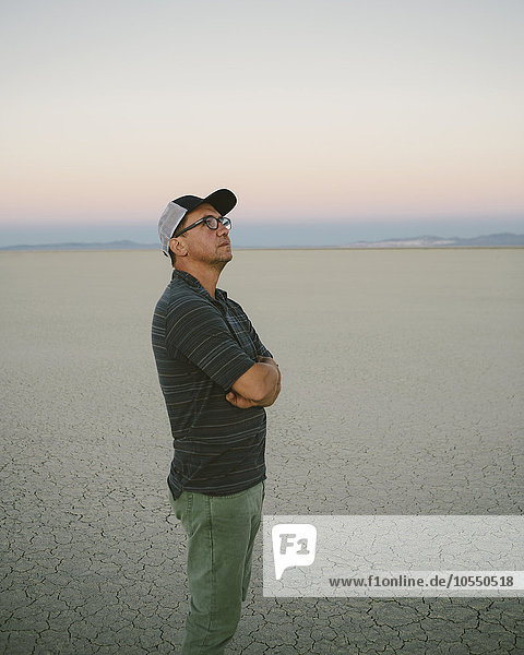 Ein Mann mittleren Alters  der in der Morgendämmerung in der Black-Rock-Wüste den Blick auf sich nimmt und sich umsieht