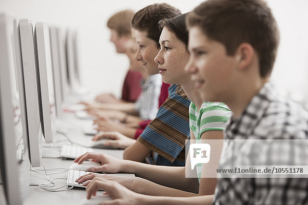 Eine Gruppe von Jugendlichen  Jungen und Mädchen  Studenten in einer Computerklasse  die an Bildschirmen arbeiten.