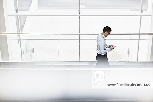 Ein Mann steht auf einem Gehsteig und überprüft sein Smartphone.