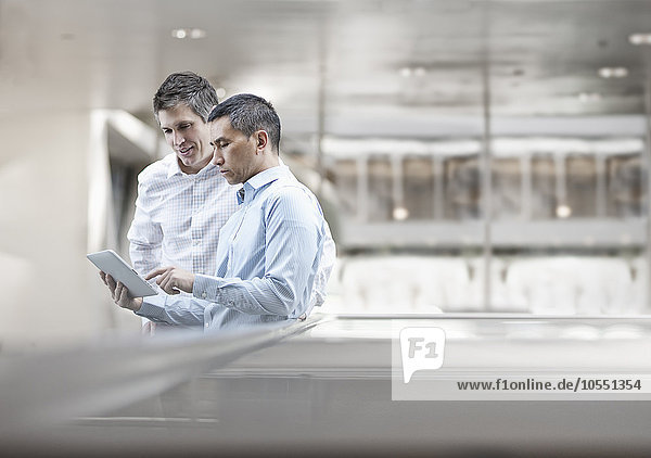 Zwei Männer  Geschäftskollegen  schauen auf einen digitalen Tablet-Bildschirm.