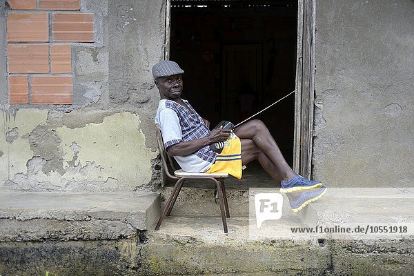 Mann sitzt mit Radio vor der Tür  afrokolumbianisches Dorf El Salto am Fluss Rio Andagueda  Departamento del Chocó  Kolumbien  Südamerika