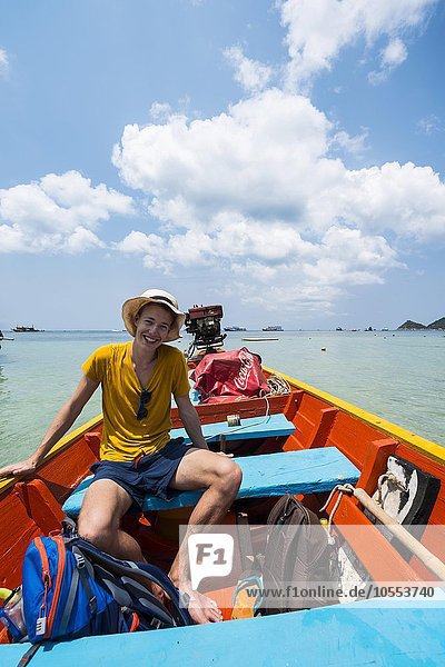 Young man sitting in longtail boat  turquoise sea  Koh Tao  Gulf of Thailand  Thailand  Asia
