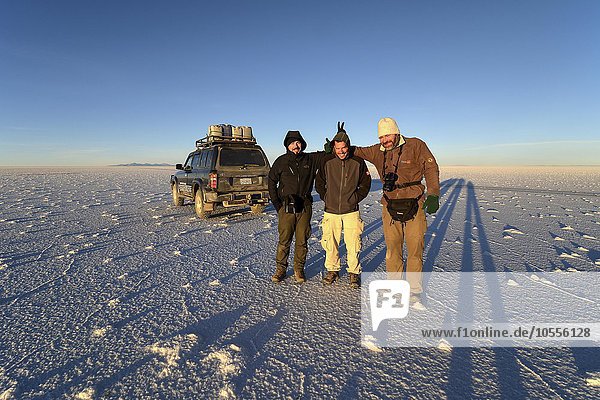 Three men and SUV on salt flat  Salar de Uyuni  Altiplano  Bolivia  South America