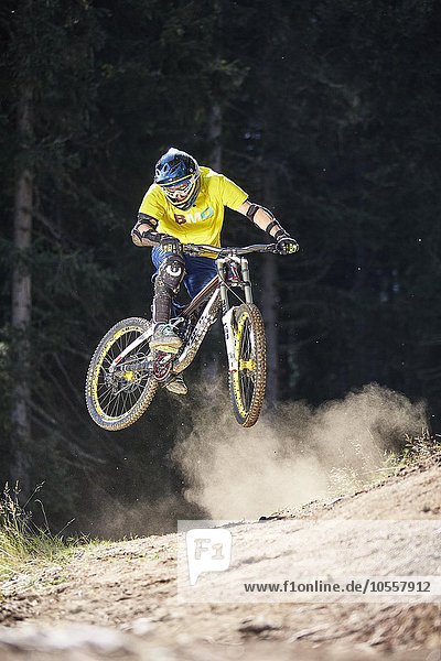 Mountainbiker  Downhill Biker springt bei einer Kante in einem Downhilltrail  Mutterer Alm  Muttereralmpark  Mutters  Innsbruck  Tirol  Österreich  Europa