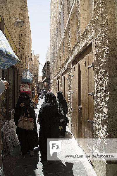 Women in hijab walking on Doha sidewalk  Doha  Qatar