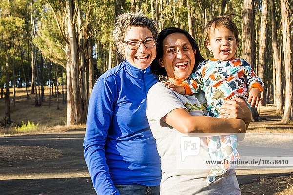 Lesbian couple holding baby in park