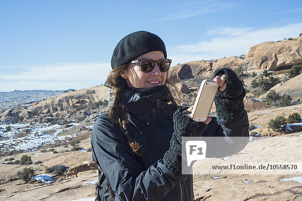 Kaukasische Frau fotografiert mit ihrem Handy auf einem Hügel