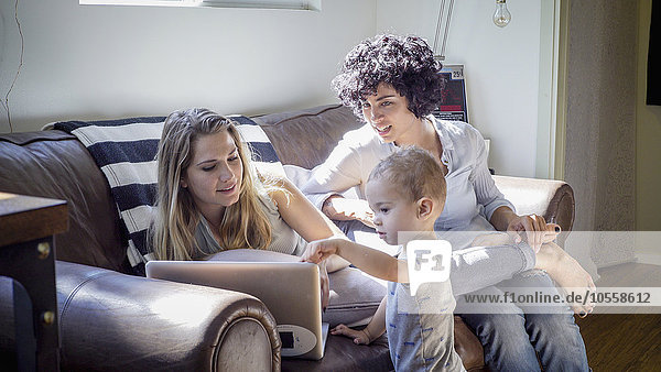Caucasian lesbian mothers and baby son on sofa