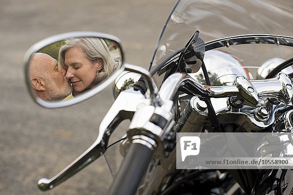 Älteres Paar küsst sich im Motorradseitenspiegel