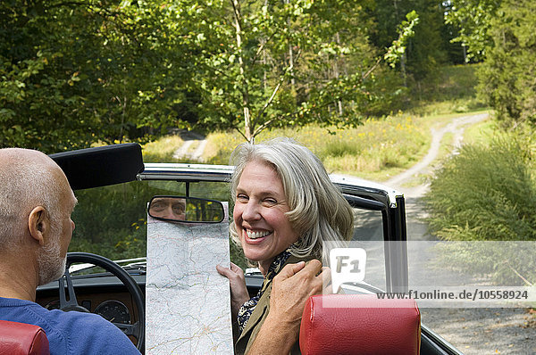 Älteres Paar fährt Cabrio auf unbefestigtem Weg