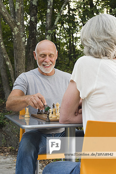 Older couple playing chess in backyard