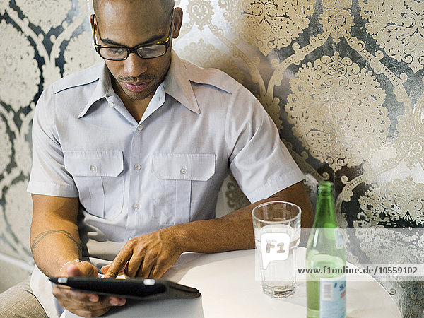 Afroamerikanischer Mann benutzt digitales Tablet in einem Restaurant