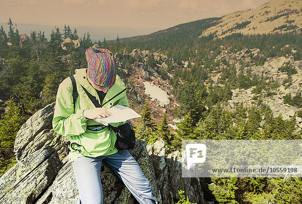 Kaukasischer Wanderer  der auf einer Bergkuppe eine Karte liest
