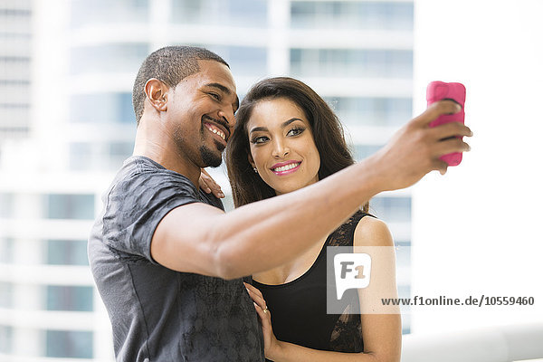 Couple taking selfie with cell phone on urban balcony