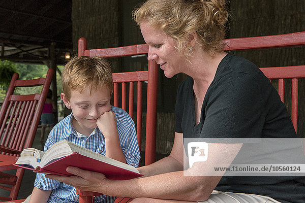 Kaukasische Mutter und Sohn lesen auf der Terrasse