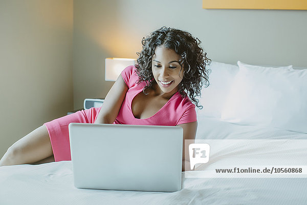 Frau benutzt Laptop auf Hotelbett