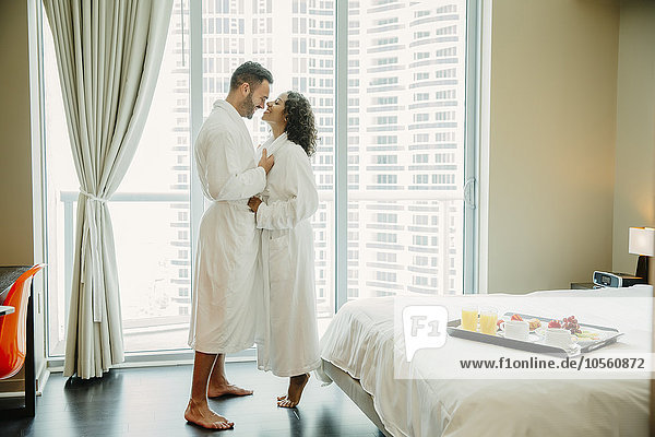 Paar umarmt sich im Bademantel im Hotelzimmer