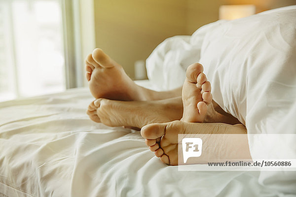 Nahaufnahme der Füße eines Paares im Bett