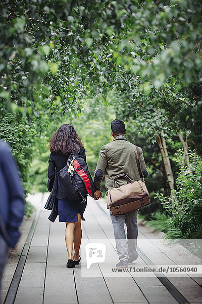 Paar geht auf Holzsteg im Park