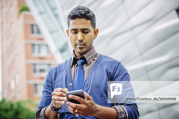 Indian businessman using cell phone outdoors