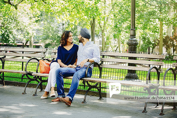 Indian couple sitting on bench in urban park