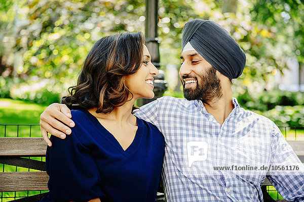 Indisches Paar  das sich auf einer Bank im Stadtpark umarmt