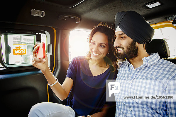 Indisches Paar macht Selfie mit Handy im Taxi