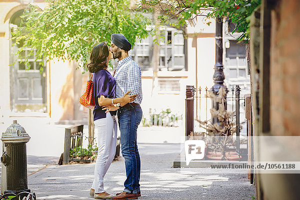Indian couple kissing on city sidewalk