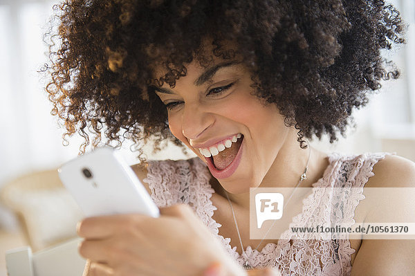 Smiling mixed race woman using cell phone