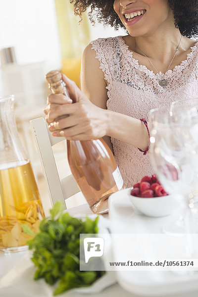 Gemischtrassige Frau öffnet eine Flasche Wein