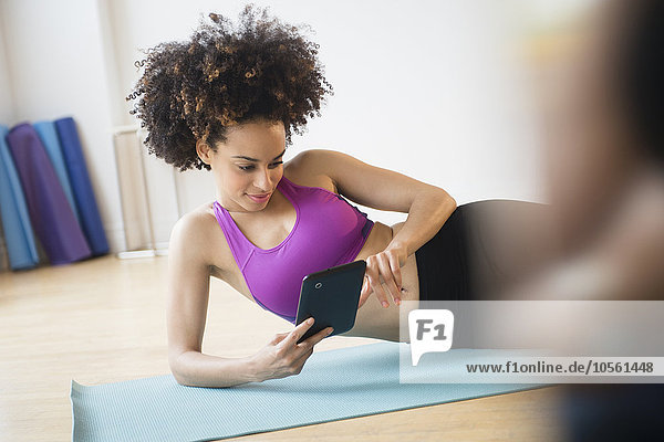 Mixed race woman working out with digital tablet in gymnasium