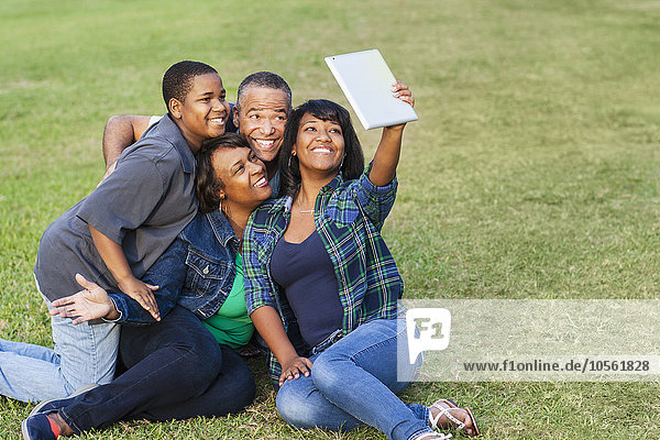 Afroamerikanische Familie macht Selfie mit digitalem Tablet im Gras