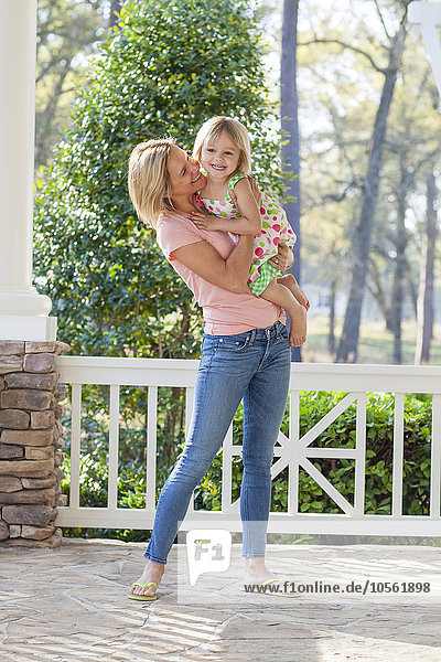 Caucasian mother holding daughter on patio