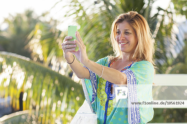 Hispanic woman taking selfie with cell phone on patio