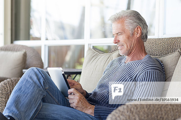 Kaukasischer Mann mit digitalem Tablet auf dem Sofa