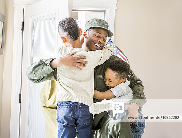 Heimkehrender Soldat umarmt Kinder an der Tür