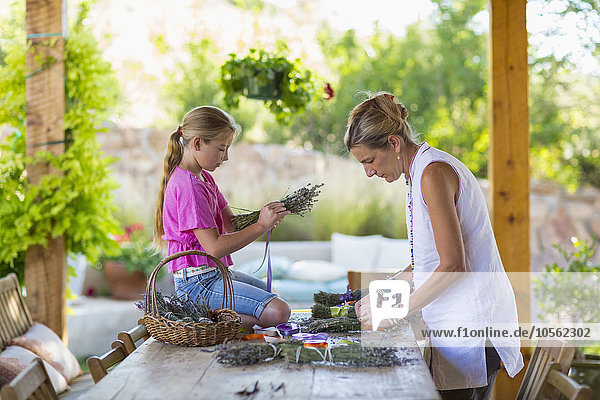 Kaukasische Mutter und Tochter bei der Herstellung von Trockenblumenbündeln