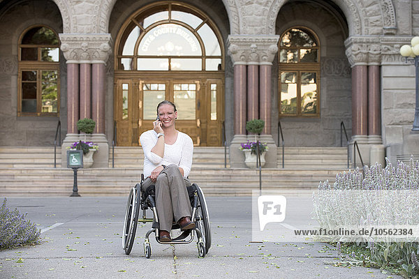 Behinderte Frau sitzt im Rollstuhl vor dem Gerichtsgebäude