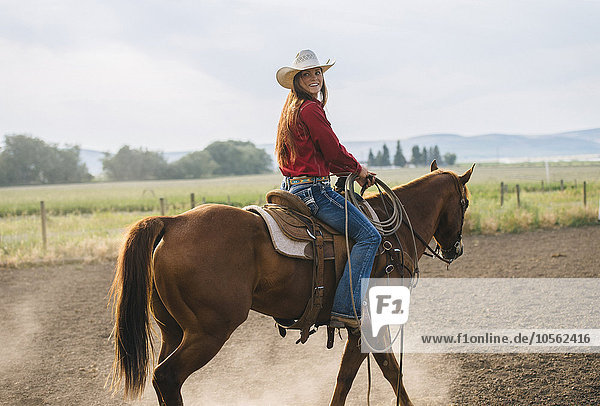 Kaukasisches Cowgirl reitet auf einer Ranch