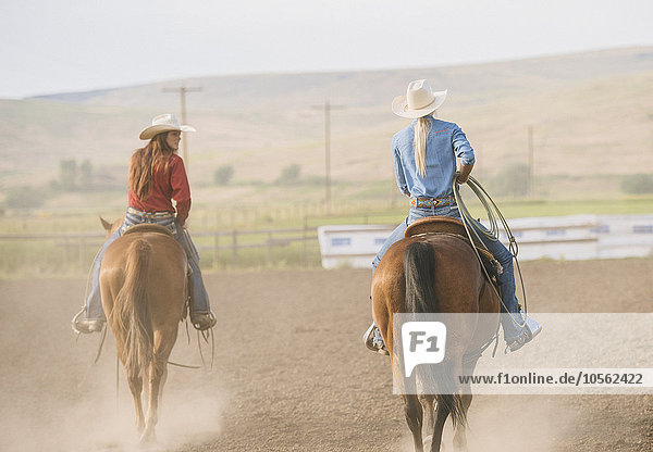 Kaukasische Cowgirls reiten auf einer Ranch