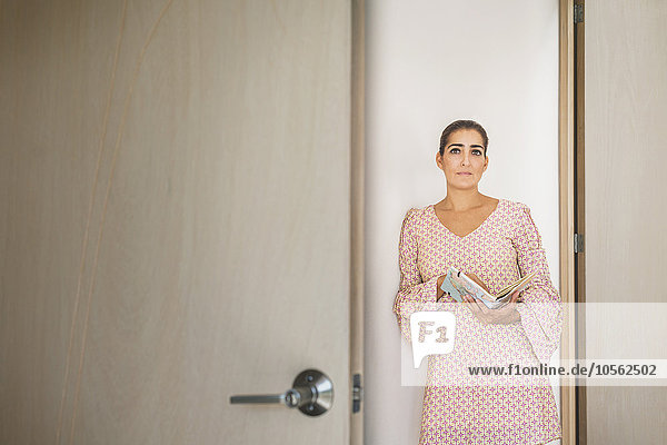 Besorgte hispanische Frau späht durch einen Türspalt