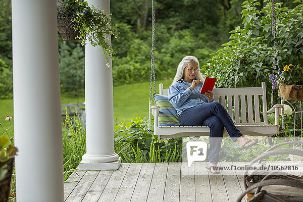 Caucasian woman using digital tablet on porch swing