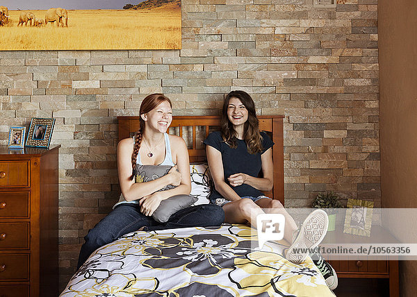 Students laughing on bed in dorm room