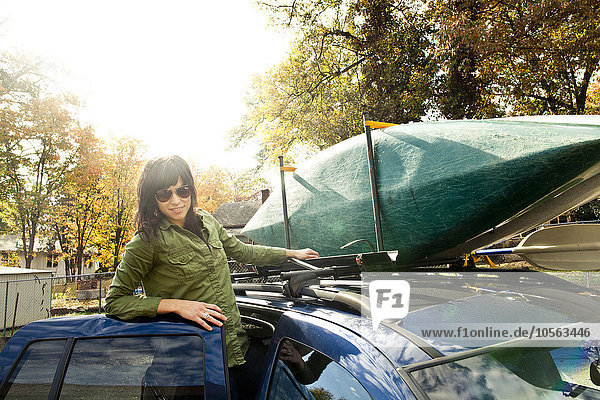 Kaukasische Frau packt Kajak auf Auto