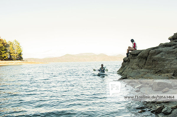 Frau beobachtet Freund beim Rudern im Kajak auf dem See