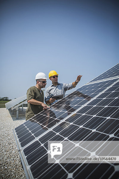 Caucasian technicians examining solar panels
