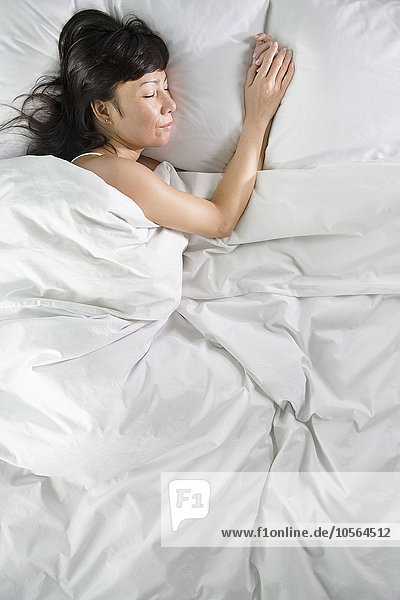 Gemischtrassige Frau schläft im Bett