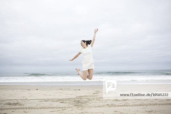 Vor Freude springende Frau am Strand